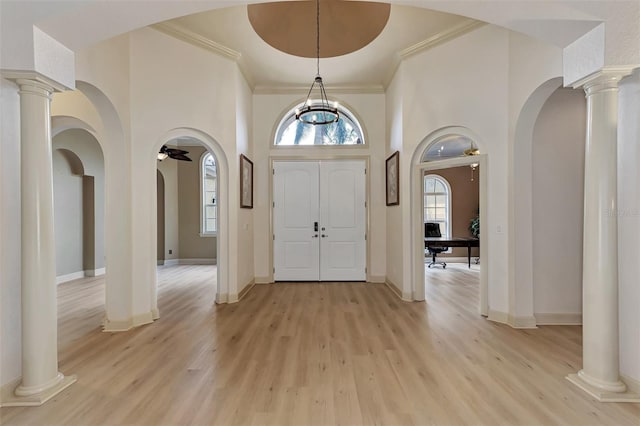 foyer with decorative columns, a healthy amount of sunlight, and light wood finished floors