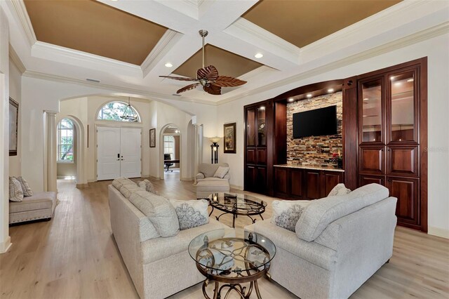 living room with coffered ceiling, beam ceiling, light hardwood / wood-style floors, ornamental molding, and ceiling fan