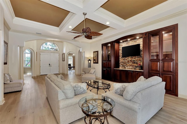 living area with arched walkways, coffered ceiling, light wood-style flooring, and crown molding