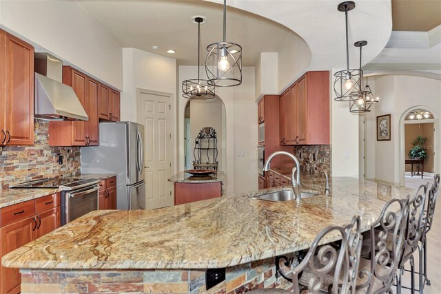 kitchen with backsplash, appliances with stainless steel finishes, sink, wall chimney range hood, and ornamental molding