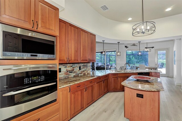 kitchen featuring light hardwood / wood-style floors, appliances with stainless steel finishes, pendant lighting, and a chandelier