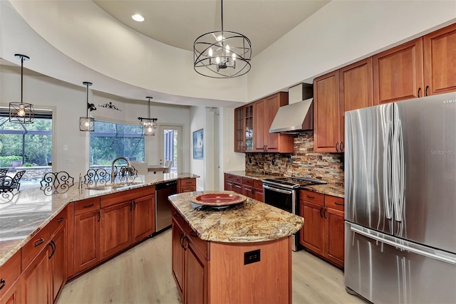 kitchen with a sink, a center island, stainless steel appliances, wall chimney exhaust hood, and brown cabinetry