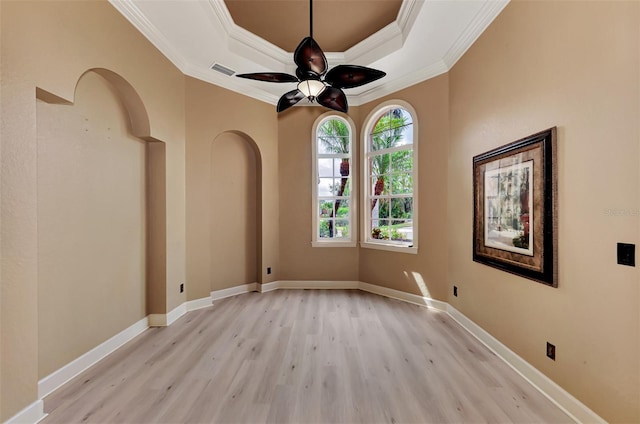 empty room featuring visible vents, baseboards, light wood-type flooring, and a tray ceiling