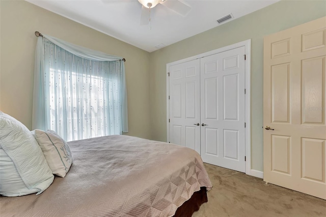 bedroom with light colored carpet, ceiling fan, and a closet