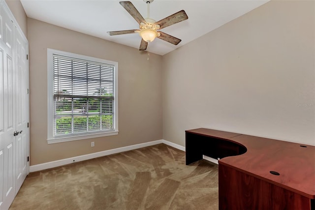 unfurnished office with ceiling fan, baseboards, and carpet