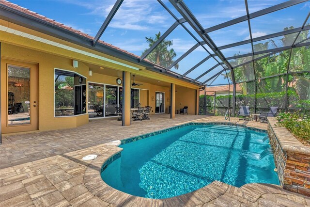 view of swimming pool featuring glass enclosure, a patio area, ceiling fan, and pool water feature