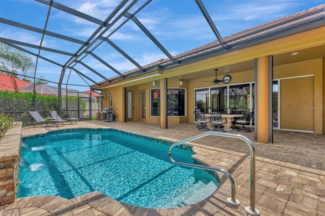 view of swimming pool featuring a lanai, a patio, pool water feature, ceiling fan, and area for grilling