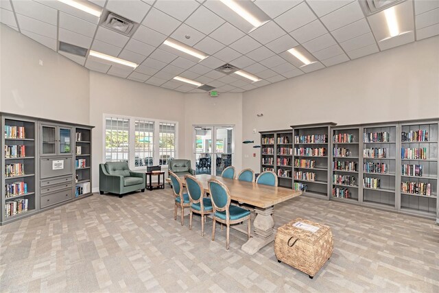 interior space with a paneled ceiling, a towering ceiling, and carpet floors