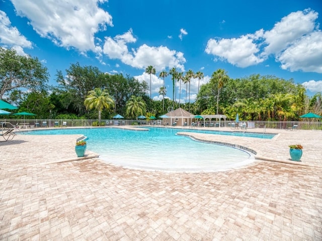 community pool with a patio and fence