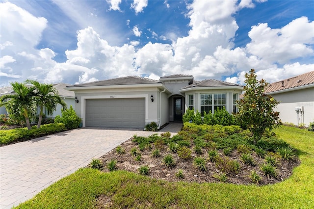 view of front of house with a tiled roof, decorative driveway, an attached garage, and stucco siding