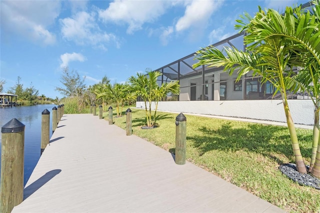 exterior space featuring a lanai, a water view, and a lawn