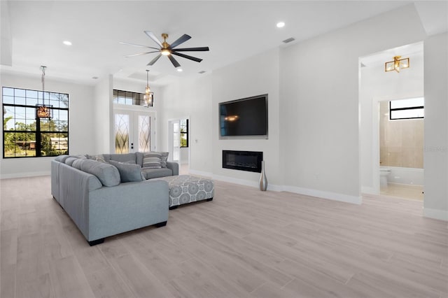 living room with ceiling fan with notable chandelier, a healthy amount of sunlight, and light hardwood / wood-style flooring