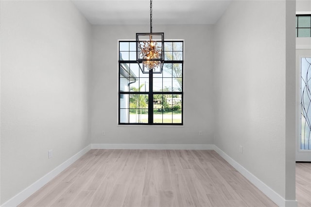 unfurnished dining area featuring a chandelier and light wood-type flooring