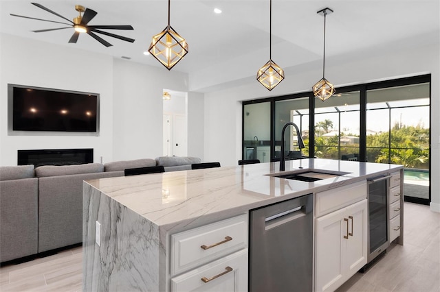 kitchen featuring light stone countertops, sink, a center island with sink, white cabinetry, and wine cooler