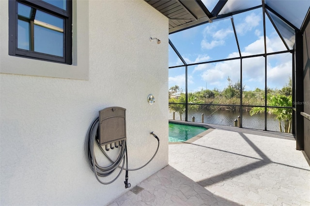 view of pool featuring a patio, a water view, and a lanai