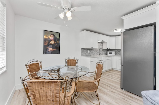 dining area with light wood-style flooring, baseboards, and ceiling fan