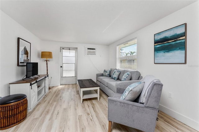 living room featuring light wood-type flooring, baseboards, and a wall mounted AC