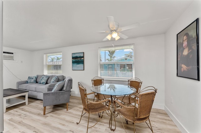 dining space featuring a wall mounted AC, light wood finished floors, baseboards, and a ceiling fan