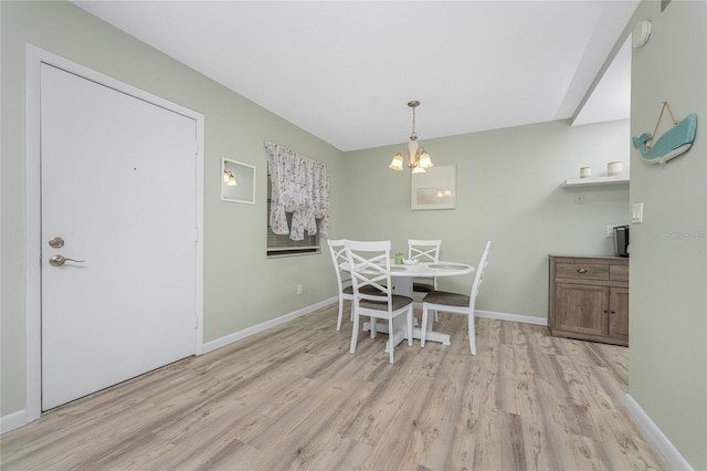 dining area with light hardwood / wood-style floors and an inviting chandelier