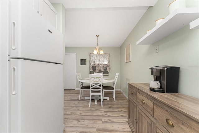 kitchen featuring light hardwood / wood-style flooring, pendant lighting, an inviting chandelier, and white refrigerator