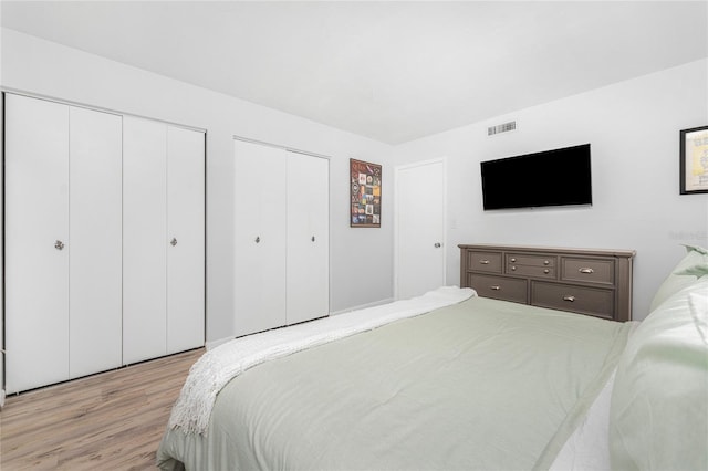 bedroom with two closets and light hardwood / wood-style floors