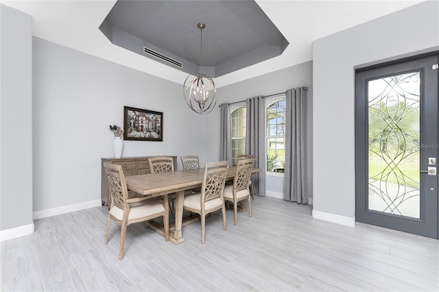 dining area with a notable chandelier, a tray ceiling, and a wealth of natural light