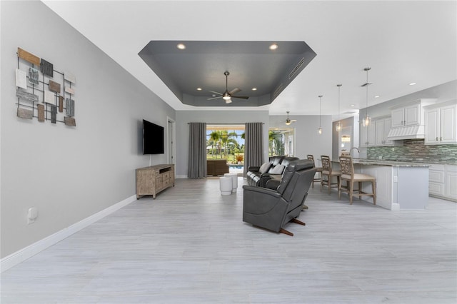 living room featuring a tray ceiling and ceiling fan