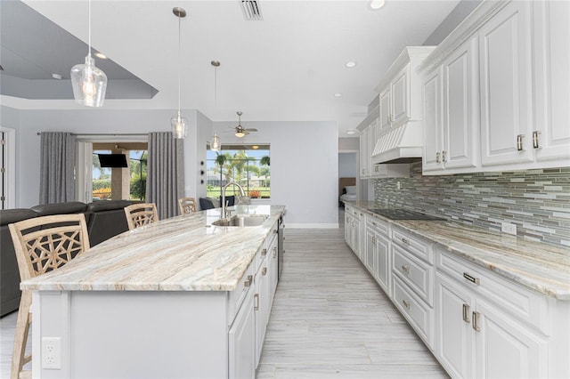 kitchen featuring a healthy amount of sunlight, white cabinetry, and an island with sink