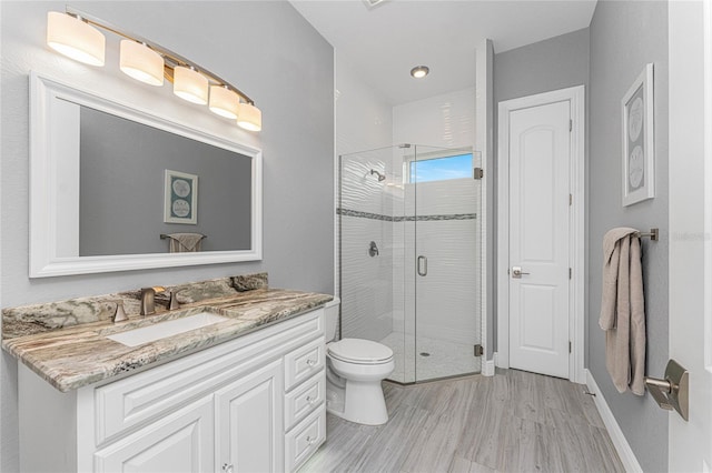 bathroom with hardwood / wood-style floors, a shower with door, vanity, and toilet