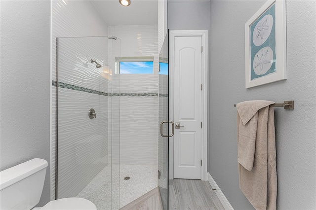 bathroom featuring a shower with door, hardwood / wood-style floors, and toilet