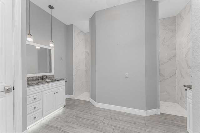 bathroom with tiled shower and vanity