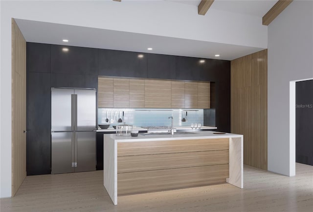 kitchen with stainless steel built in refrigerator, a center island with sink, light hardwood / wood-style floors, tasteful backsplash, and sink