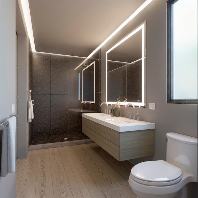 bathroom featuring hardwood / wood-style floors, toilet, tiled shower, and vanity