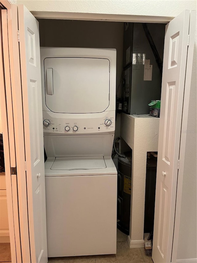 laundry area with stacked washer and clothes dryer and light tile patterned floors