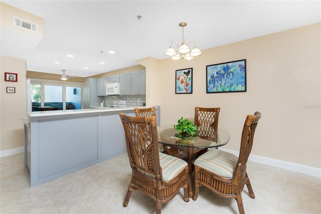 dining space with ceiling fan with notable chandelier and sink