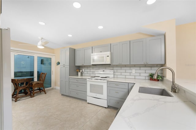 kitchen with white appliances, light stone countertops, sink, and ceiling fan