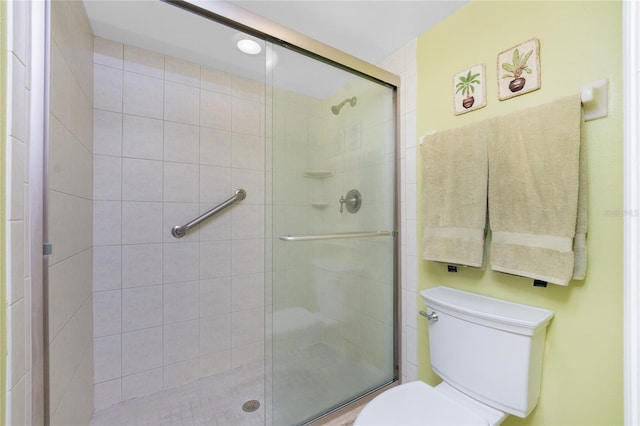 bathroom with a shower with door and toilet