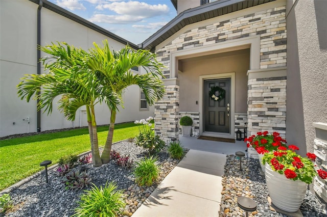 property entrance with a yard, stone siding, and stucco siding