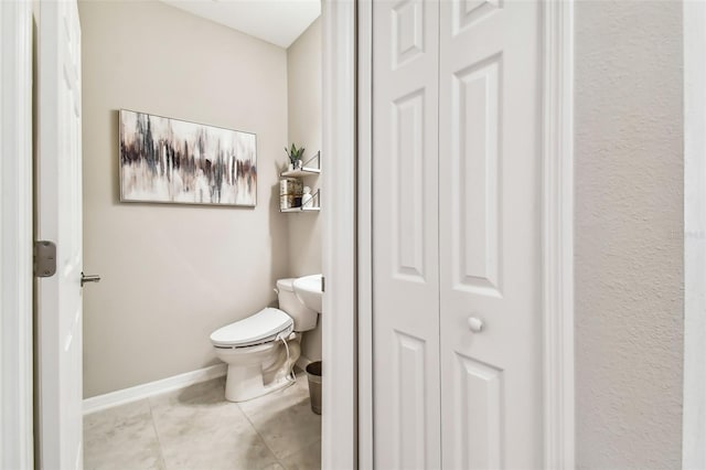 bathroom featuring a closet, baseboards, toilet, and tile patterned flooring