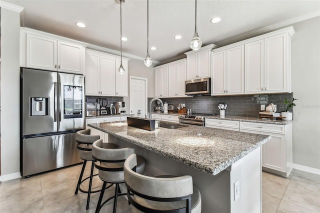 kitchen with light tile patterned flooring, a kitchen island with sink, a sink, decorative backsplash, and appliances with stainless steel finishes