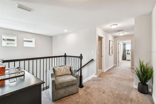 sitting room featuring an upstairs landing, visible vents, carpet flooring, and baseboards