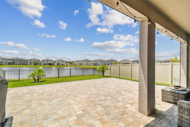 view of patio featuring a residential view, a fenced backyard, and a water view