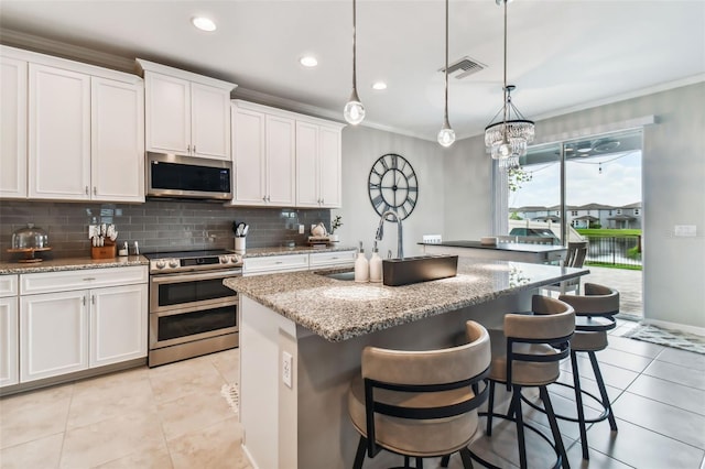 kitchen with light tile patterned flooring, a center island, stainless steel appliances, and crown molding