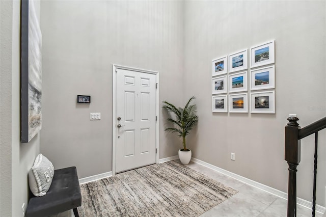 foyer with a high ceiling, stairway, and baseboards