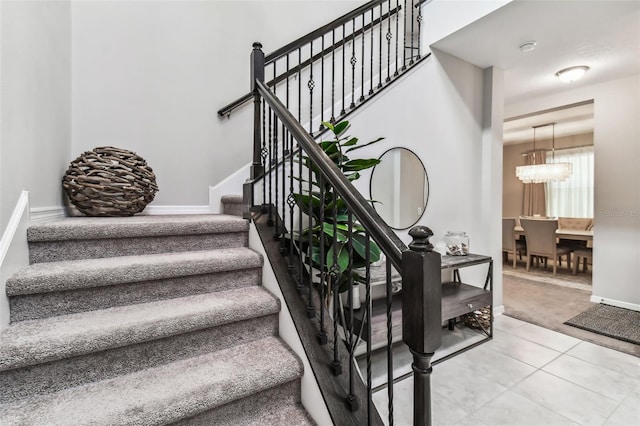 stairs with tile patterned flooring, an inviting chandelier, baseboards, and carpet floors