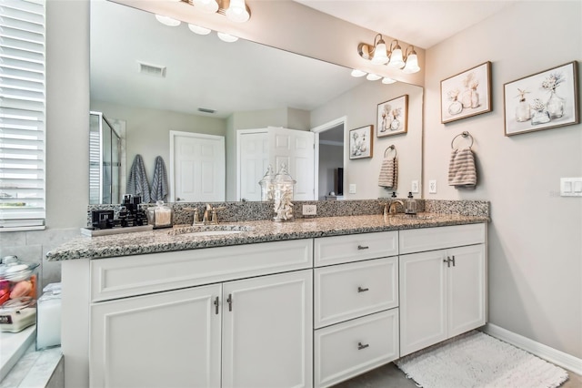 full bath featuring double vanity, baseboards, visible vents, and a sink