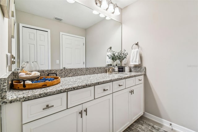 full bath with a sink, visible vents, baseboards, and double vanity