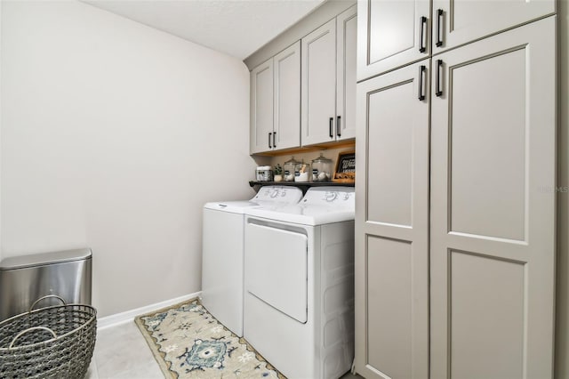 laundry area featuring baseboards, cabinet space, and separate washer and dryer