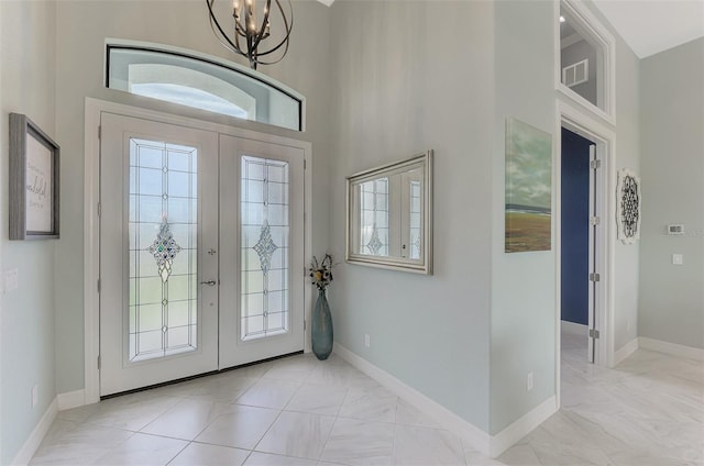 entryway with french doors, a chandelier, and a high ceiling