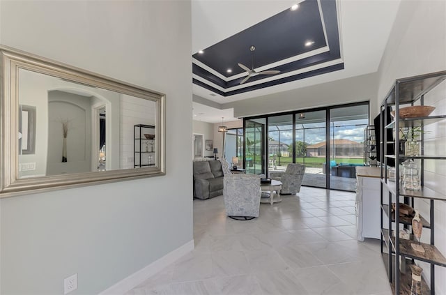 living room featuring a tray ceiling, ceiling fan, and crown molding